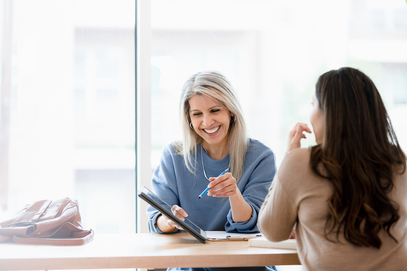 A female independent insurance agent shows customers policy options on a tablet.